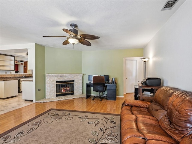 14719 Juniper St, Hesperia, CA 92345 - living room featuring a desk, ceiling fan, light wood-type flooring, and a brick fireplace