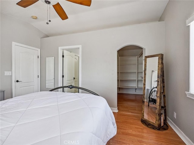 14719 Juniper St, Hesperia, CA 92345 - bedroom with light wood-style floors, arched walkways, lofted ceiling, a walk in closet, and a ceiling fan