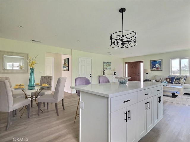 378 W Rosa Parks Rd, Palm Springs, CA 92262 - kitchen with open floor plan, light wood finished floors, a kitchen island, and white cabinets
