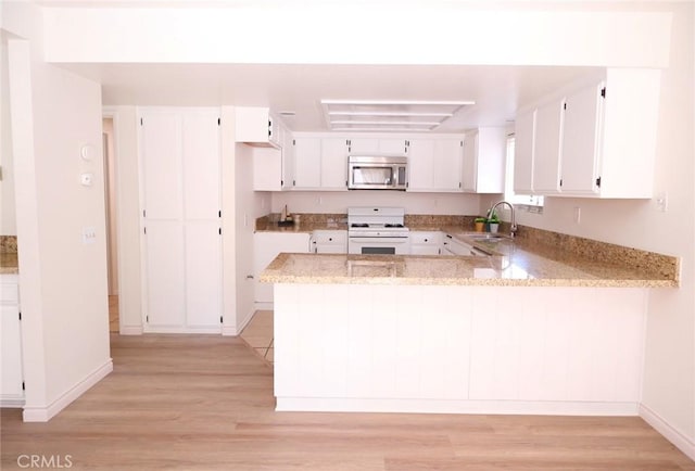 1387 Sycamore Ln, San Bernardino, CA 92408 - kitchen featuring stainless steel microwave, white stove, light wood-style floors, and a peninsula