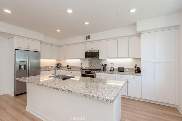 1851 S Union St Unit 10, Anaheim, CA 92805 - kitchen featuring stainless steel appliances, light wood finished floors, white cabinets, a center island with sink, and recessed lighting