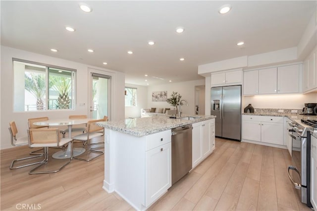 1851 S Union St Unit 10, Anaheim, CA 92805 - kitchen featuring stainless steel appliances, light wood finished floors, a center island with sink, white cabinetry, and recessed lighting