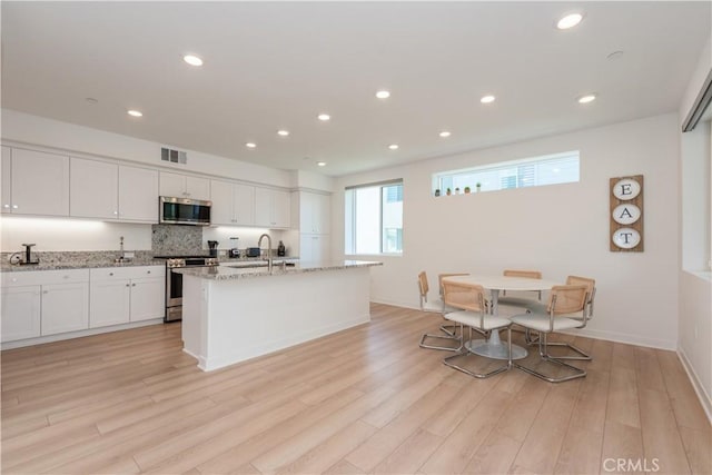 1851 S Union St Unit 10, Anaheim, CA 92805 - kitchen featuring stainless steel appliances, white cabinets, light wood-style flooring, light stone countertops, and recessed lighting