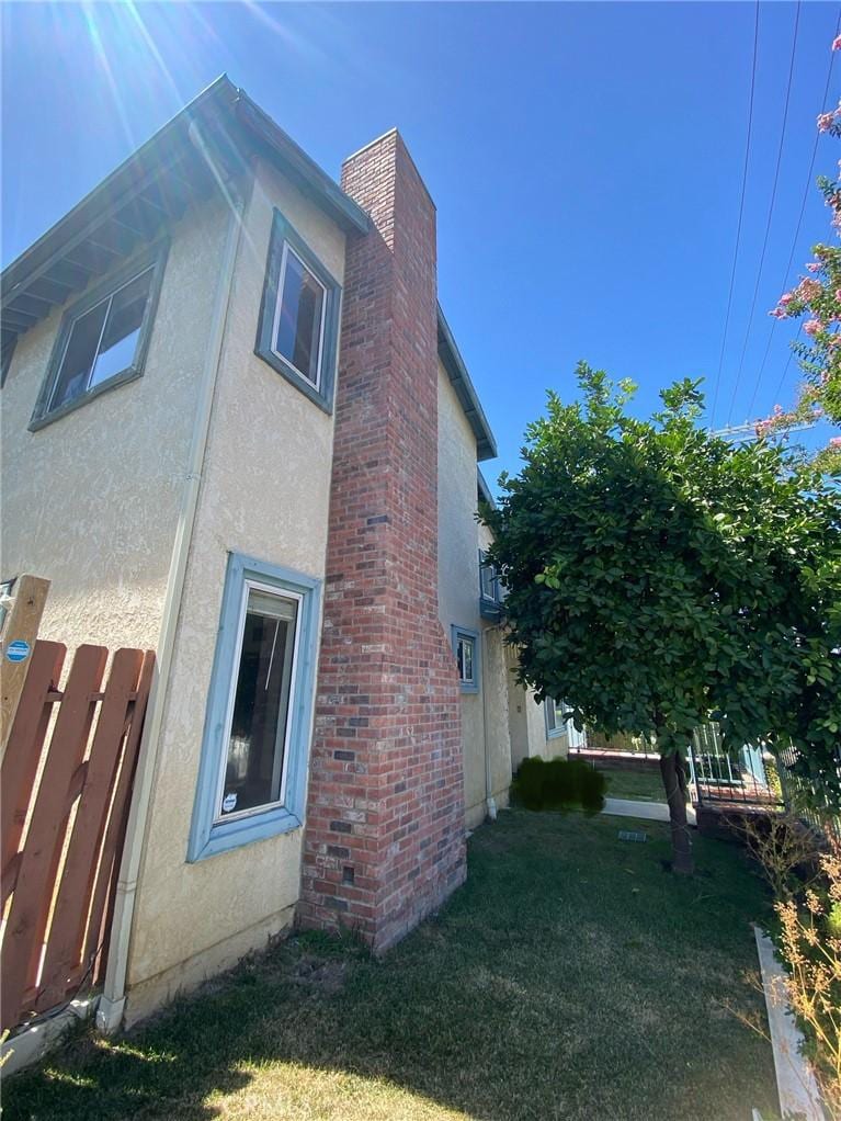 7527 Tampa Ave Unit 1, Reseda, CA 91335 - view of property exterior featuring stucco siding, a chimney, and a lawn