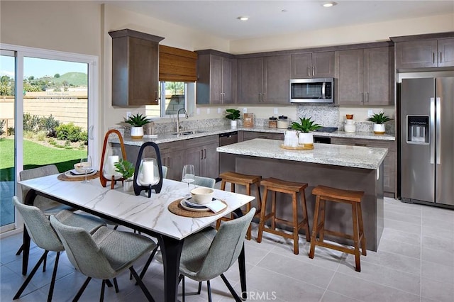 8176 Perada St, Jurupa Valley, CA 92509 - kitchen featuring stainless steel appliances, dark brown cabinets, a center island, light tile patterned flooring, and a kitchen breakfast bar