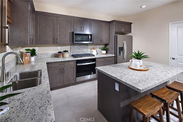 8176 Perada St, Jurupa Valley, CA 92509 - kitchen with appliances with stainless steel finishes, a breakfast bar, dark brown cabinets, light stone countertops, and recessed lighting