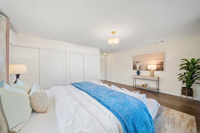 12218 Academy Way, Artesia, CA 90701 - bedroom with wood finished floors, multiple closets, a textured ceiling, and a wall mounted AC