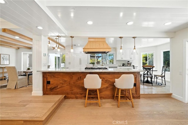 24901 Del Monte St, Laguna Hills, CA 92653 - kitchen featuring custom range hood, light wood-style floors, a breakfast bar, white cabinetry, and recessed lighting