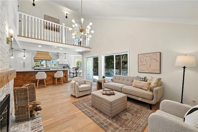 24901 Del Monte St, Laguna Hills, CA 92653 - living area featuring light wood-style floors, ornamental molding, a chandelier, a stone fireplace, and a towering ceiling