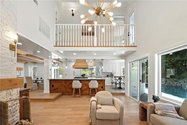 24901 Del Monte St, Laguna Hills, CA 92653 - living area featuring light wood-style flooring, a high ceiling, a chandelier, and ornamental molding
