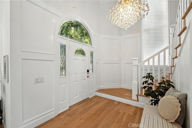 24901 Del Monte St, Laguna Hills, CA 92653 - entrance foyer with light wood-style flooring, a decorative wall, a chandelier, stairway, and a high ceiling