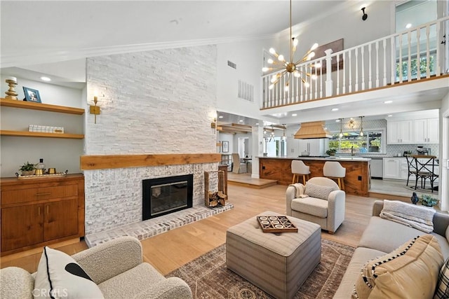 24901 Del Monte St, Laguna Hills, CA 92653 - living room with light wood-style flooring, a high ceiling, ornamental molding, a chandelier, and a fireplace