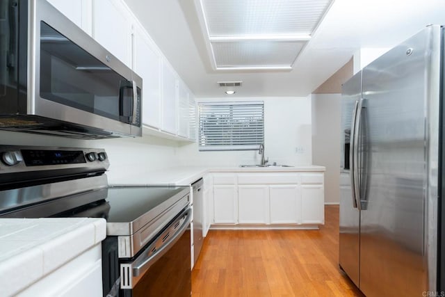 10500 Flora Azalea Ct, Santee, CA 92071 - kitchen with stainless steel appliances, white cabinetry, light wood finished floors, and tile countertops