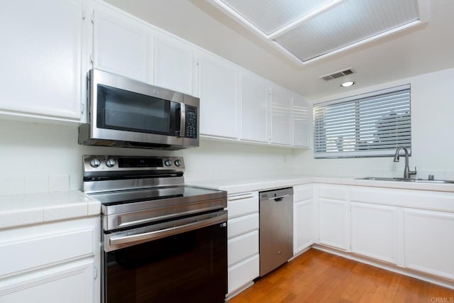 10500 Flora Azalea Ct, Santee, CA 92071 - kitchen with stainless steel appliances, tile counters, white cabinets, and light wood-style flooring