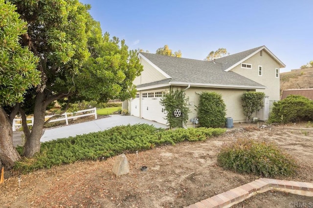 1772 Treseder Cir, El Cajon, CA 92019 - view of side of home with driveway, an attached garage, stucco siding, and a shingled roof