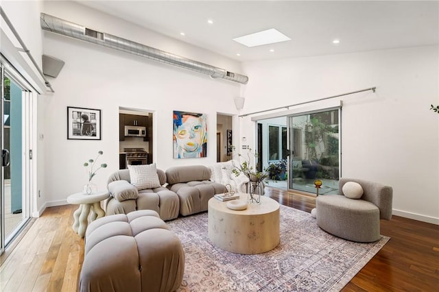2531 N Commonwealth Ave, Los Angeles, CA 90027 - living area featuring a skylight, plenty of natural light, wood finished floors, high vaulted ceiling, and recessed lighting