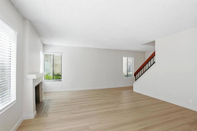 8373 Suntree Pl, San Diego, CA 92119 - unfurnished living room with stairway, light wood-style floors, a textured ceiling, and a fireplace