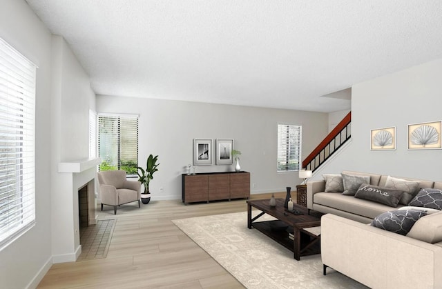 8373 Suntree Pl, San Diego, CA 92119 - living area featuring light wood-style floors, stairway, a textured ceiling, and a fireplace with flush hearth