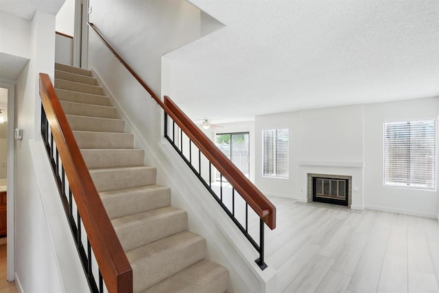 8373 Suntree Pl, San Diego, CA 92119 - staircase featuring a fireplace with flush hearth, a textured ceiling, and ceiling fan