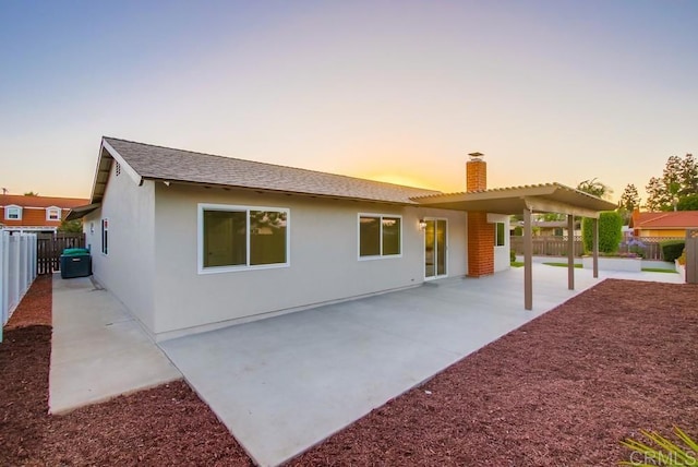6947 Wallsey Dr, San Diego, CA 92119 - back of property at dusk featuring a chimney, a fenced backyard, stucco siding, and a patio area