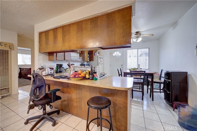 2120 Ocean St, Oceano, CA 93445 - kitchen featuring a heating unit, a peninsula, a textured ceiling, light countertops, and brown cabinets