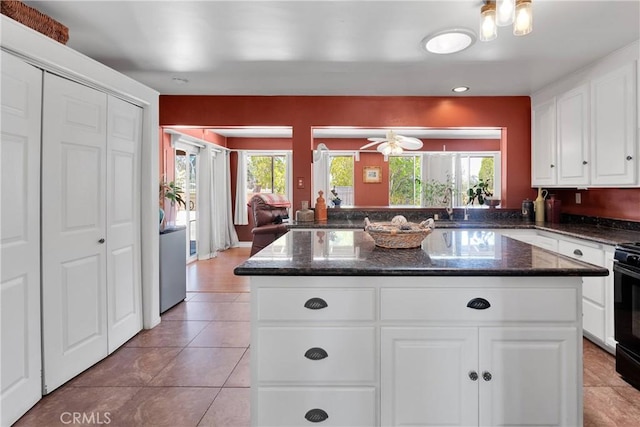 19955 Chickasaw Rd, Apple Valley, CA 92307 - kitchen with a kitchen island, white cabinetry, dark stone countertops, light tile patterned floors, and a ceiling fan