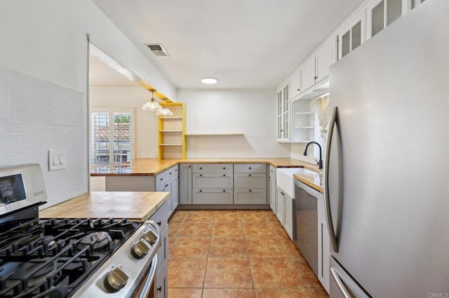 1220 Palomar Ter, Escondido, CA 92027 - kitchen with appliances with stainless steel finishes, glass insert cabinets, open shelves, light tile patterned floors, and gray cabinetry