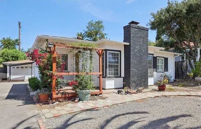 1220 Palomar Ter, Escondido, CA 92027 - view of front facade featuring a chimney, an outbuilding, stucco siding, a garage, and driveway