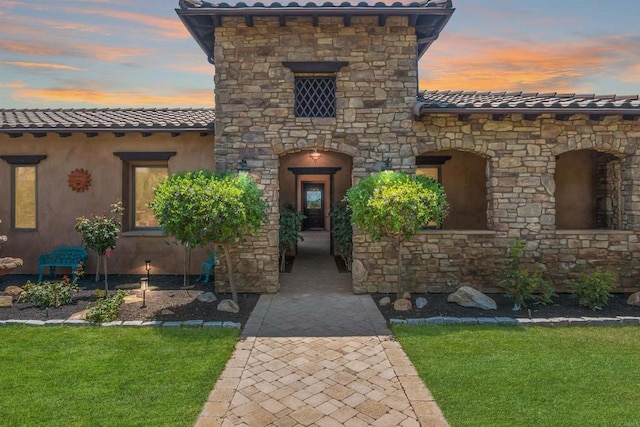 14786 Cool Valley Ranch Rd, Valley Center, CA 92082 - exterior entry at dusk featuring stone siding, a tile roof, and a yard