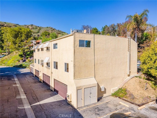 9531 Via Ricardo, Sun Valley, CA 91504 - view of side of property featuring stucco siding, asphalt driveway, a garage, and a mountain view