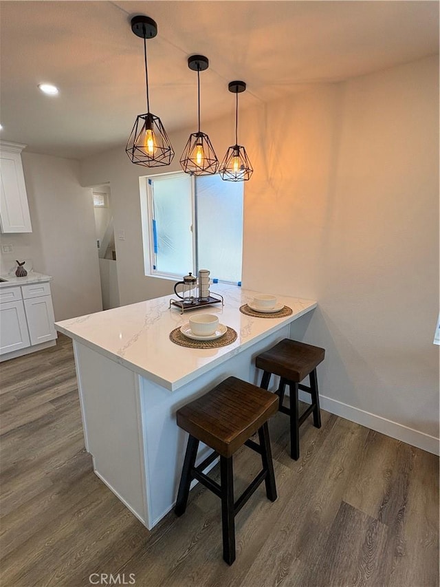1526 W 54th St, Los Angeles, CA 90062 - kitchen featuring dark wood-style floors, white cabinetry, a peninsula, a kitchen breakfast bar, and recessed lighting