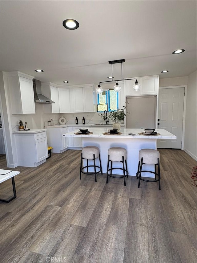 1526 W 54th St, Los Angeles, CA 90062 - kitchen featuring wall chimney exhaust hood, dark wood-style floors, white cabinets, a breakfast bar area, and recessed lighting