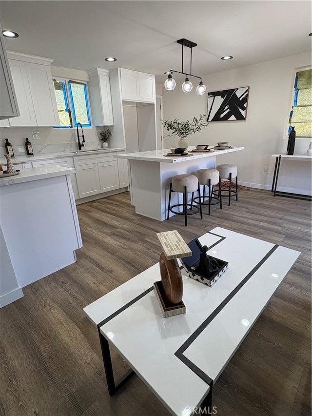 1526 W 54th St, Los Angeles, CA 90062 - kitchen with dark wood-type flooring, white cabinetry, a kitchen breakfast bar, light countertops, and recessed lighting