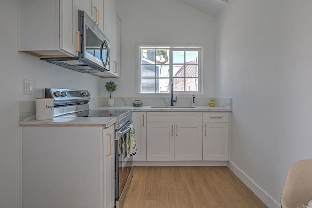 4711 Landis St, San Diego, CA 92105 - kitchen with appliances with stainless steel finishes, light wood finished floors, light countertops, white cabinetry, and vaulted ceiling