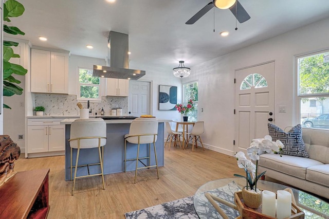 4711 Landis St, San Diego, CA 92105 - kitchen with island exhaust hood, light wood-type flooring, tasteful backsplash, white cabinetry, and recessed lighting