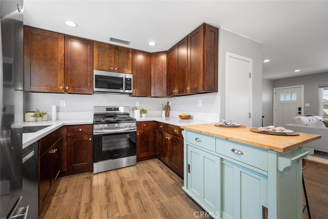 4513 E Cervato St, Long Beach, CA 90815 - kitchen with appliances with stainless steel finishes, light wood finished floors, butcher block counters, a kitchen bar, and recessed lighting