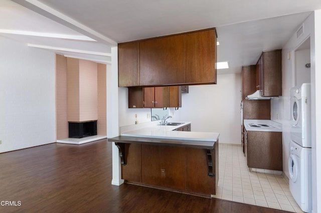 777 E Valley Blvd Unit 142, Alhambra, CA 91801 - kitchen featuring stacked washing machine and dryer, a peninsula, light wood-style floors, a breakfast bar, and under cabinet range hood