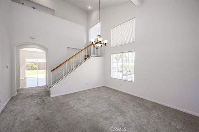 13056 Hagar St, Sylmar, CA 91342 - unfurnished living room with a chandelier, carpet, a towering ceiling, stairway, and arched walkways