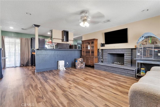 13144 Algonquin Rd, Apple Valley, CA 92308 - living room with a textured ceiling, ceiling fan, healthy amount of natural light, wood finished floors, and a fireplace