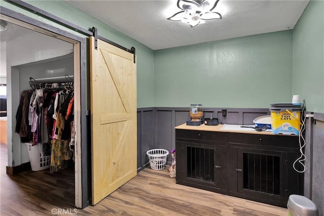 13144 Algonquin Rd, Apple Valley, CA 92308 - office featuring a barn door, wood finished floors, wainscoting, a textured ceiling, and a decorative wall