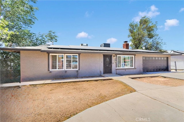 13144 Algonquin Rd, Apple Valley, CA 92308 - ranch-style home with concrete driveway, a garage, roof mounted solar panels, a chimney, and stucco siding