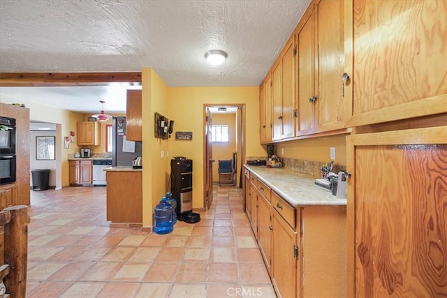 60810 Sunrise Rd, Whitewater, CA 92282 - kitchen with dishwasher, light countertops, a textured ceiling, light stone finish floors, and brown cabinetry