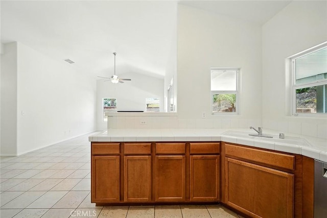 12038 Diego Ct, Moreno Valley, CA 92557 - kitchen featuring a ceiling fan, healthy amount of natural light, vaulted ceiling, brown cabinetry, and light tile patterned floors
