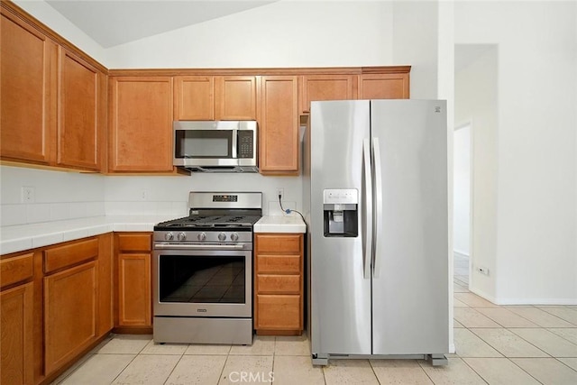 12038 Diego Ct, Moreno Valley, CA 92557 - kitchen with appliances with stainless steel finishes, lofted ceiling, tile countertops, light tile patterned floors, and brown cabinetry