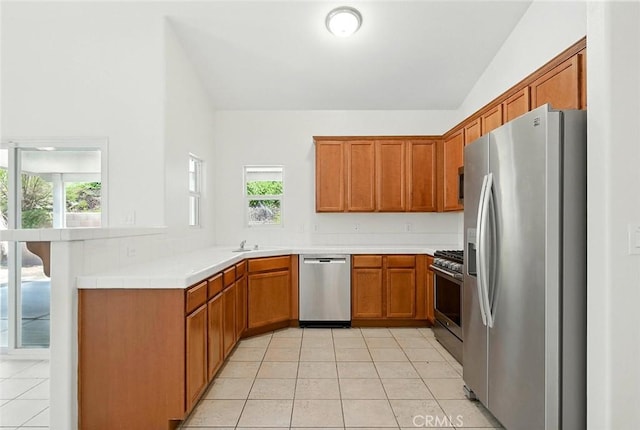 12038 Diego Ct, Moreno Valley, CA 92557 - kitchen with appliances with stainless steel finishes, a peninsula, light tile patterned flooring, lofted ceiling, and brown cabinets