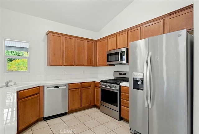 12038 Diego Ct, Moreno Valley, CA 92557 - kitchen with stainless steel appliances, vaulted ceiling, tile countertops, brown cabinetry, and light tile patterned flooring