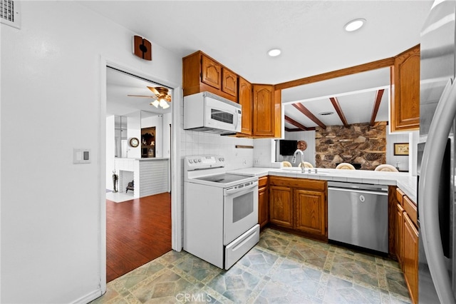 9802 Swallow Ln, Garden Grove, CA 92841 - kitchen featuring appliances with stainless steel finishes, brown cabinetry, a ceiling fan, beamed ceiling, and a fireplace
