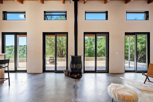 4190 Shadow Canyon Rd, Templeton, CA 93465 - doorway to outside with beam ceiling, a wood stove, a high ceiling, and concrete flooring