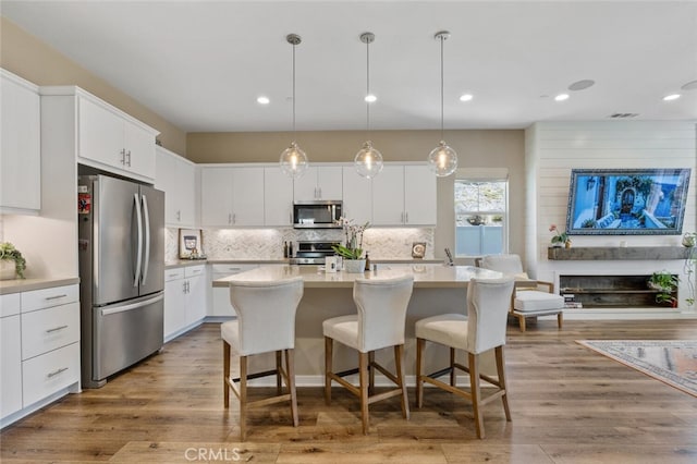 28816 Sedge Ln, Saugus, CA 91350 - kitchen with appliances with stainless steel finishes, light countertops, decorative backsplash, white cabinetry, and a center island with sink