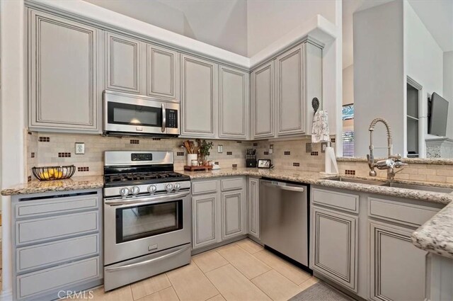 27242 Cabrillo Dr, Menifee, CA 92586 - kitchen featuring appliances with stainless steel finishes, backsplash, light tile patterned floors, and light stone countertops